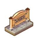 Shire Signpost – TileShire TileShire: Wooden archway sign reading “SHIRE” above a gray cobblestone tile path.